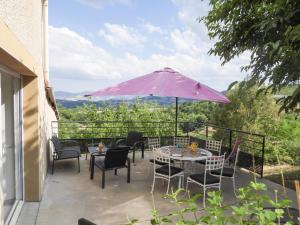 a patio with a table and chairs and a purple umbrella at Les chaillées in Saint-Romain-en-Jarez