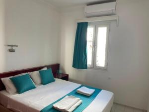 a bed with blue and white pillows and a window at Villa Nergis in Bitez