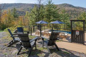 a deck with chairs and a table with umbrellas at Fawn Hill Elevated Log Cabin w Year-Round Pool in Phoenicia