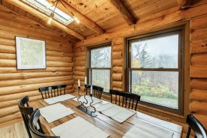 a dining room with a table and chairs and windows at Fawn Hill Elevated Log Cabin w Year-Round Pool in Phoenicia