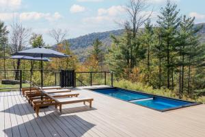 a deck with a swimming pool and an umbrella at Fawn Hill Elevated Log Cabin w Year-Round Pool in Phoenicia