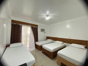 a room with three beds and a window at Dapdap Shorelines Beachfront Villa in Camotes Islands
