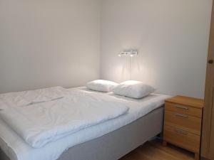 a white bed with two pillows and a night stand at Lakeview 4BR with Sauna & EV Parking in Åre +8 photos