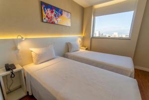 two beds in a small room with a window at Transamerica Fit Serra in Serra