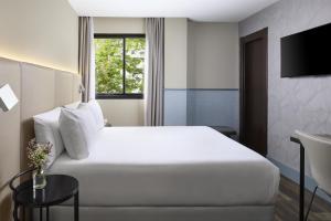 a hotel room with a white bed and a table at NH Ciudad de Santander in Santander