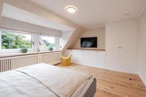 a white bedroom with a bed and a tv at Dolle's Hüs in Wenningstedt