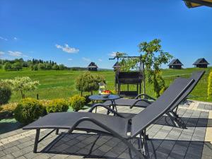 a patio with a table and chairs and a field at Osada Wichrówka domki ze strefą SPA, basenem letnim i widokiem na góry in Dursztyn