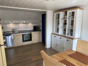a kitchen with white cabinets and a dining table at Ferienwohnung Strandkrabbe Ockholm in Ockholm