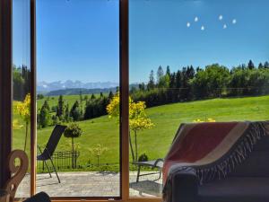 a living room with a view of a green field at Osada Wichrówka domki ze strefą SPA, basenem letnim i widokiem na góry in Dursztyn +177 photos