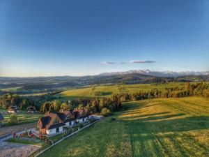 an aerial view of a house in a field at Osada Wichrówka domki ze strefą SPA, basenem letnim i widokiem na góry in Dursztyn