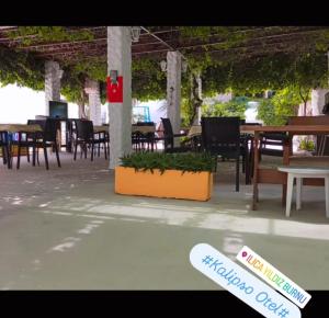 an outdoor patio with tables and chairs and a sign at Kalipso motel in Çeşme