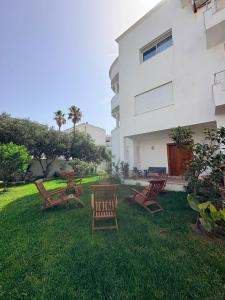 a group of chairs sitting in the grass next to a building at Appartement de luxe, Résidence les 5 étoiles, Bizerte in Zarzouna