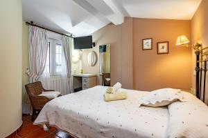 a bedroom with a white bed and a chair at Apto rurales y habitaciones MONTE CAORU - CABRALES apartahotel in Arenas de Cabrales