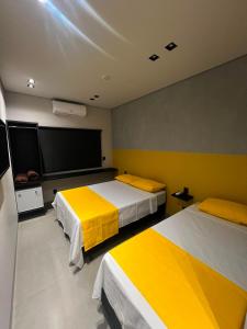a room with two beds and a flat screen tv at Pling Hotel in Jataí
