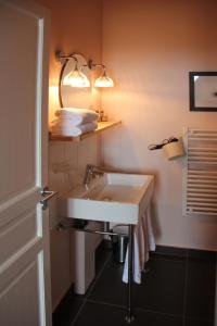 La salle de bains est pourvue d'un lavabo blanc et d'un miroir. dans l'établissement Hôtel Courtille de Solutré, à Solutré-Pouilly