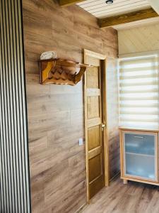 a room with a wooden wall with a door and a tv at Ezermala in Dagda