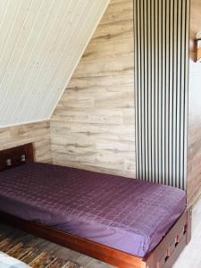 a bed in a room with a wooden wall at Ezermala in Dagda