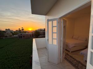 an open door to a bedroom with the sunset in the background at Star - private apartments in Luxor