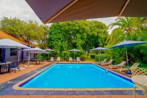 a swimming pool with tables and chairs and umbrellas at Kasimba Boutique Hotel in Gaborone