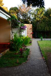 a brick walkway next to a house with flowers at Savanna Tree Apartments - self catering town center in Livingstone