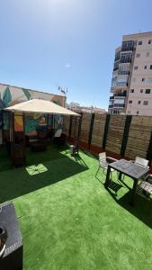 a patio with green grass and a large umbrella at Tenerife Experience Hostel in Santa Cruz de Tenerife