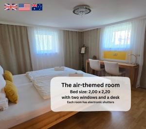 a room with a bed and a desk with two windows at Dreamly Suites Oslip in Oslip