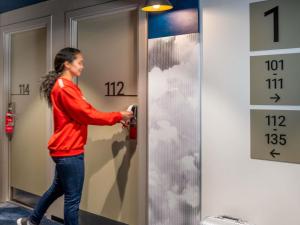 a woman is unlocking a door with clouds painted on it at Ibis Barcelona Aeropuerto Viladecans in Viladecáns