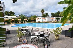 a patio with tables and chairs next to a swimming pool at Villaggio Artemide in Giardini Naxos