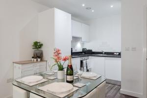 a white kitchen with a table with a bottle of wine at Liver Building View in Liverpool