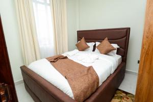 a large bed with brown and white sheets and pillows at Maraluxe Resoert & Spa in Nakuru