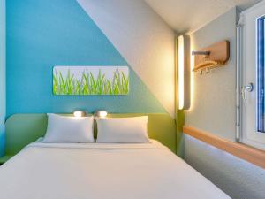 a bed in a room with a blue and green wall at ibis budget Hotel Luzern City in Lucerne