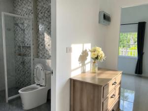 a bathroom with a toilet and a vase of flowers on a counter at เอกสิริ รีสอร์ต in Amphoe Tha Chana +19 photos
