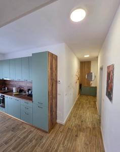 a kitchen with blue cabinets and a wooden floor at Sakura Residence Felix in Sînmartin