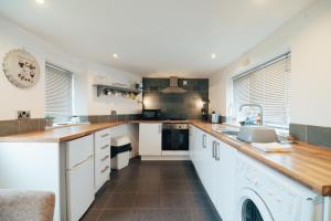 a kitchen with white cabinets and wooden counter tops at The Welsh Welcome in Pen-y-groes +6 photos