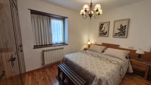 a bedroom with a bed and a window and a chandelier at Apartamentos Nogueret in Benasque +9 photos