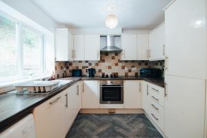 a kitchen with white cabinets and a sink at The Coastal Breeze in Porthmadog