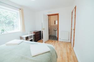 a bedroom with a bed and a desk and a window at The Coastal Breeze in Porthmadog