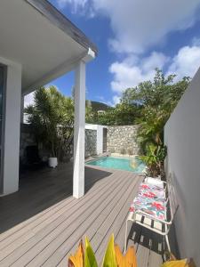 a wooden deck with a swimming pool and a house at Stylish villa with private pool in Koolbaai in Koolbaai