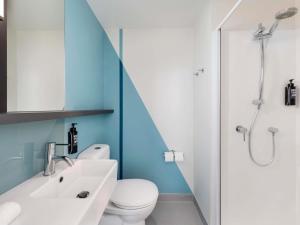 a bathroom with a toilet and a sink and a shower at ibis Budget Auckland Airport in Auckland +33 photos