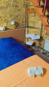 a bedroom with a bed with blue sheets and a stone wall at Refúgio do Casal in Lousã