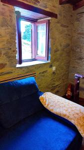 a bedroom with a blue bed with a window at Refúgio do Casal in Lousã