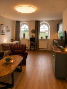 a living room with a table and two windows at Ferienwohnungen Blischke in Carolinensiel