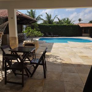 a patio with a table and chairs next to a pool at Ventos e Dunas Cumbuco in Cumbuco