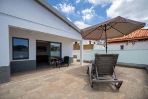 a rocking chair with an umbrella on a patio at Casa Turalves - By WeHostMadeira in Porto Santo