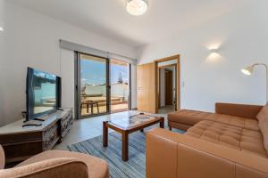 a living room with a couch and a flat screen tv at Casa Turalves - By WeHostMadeira in Porto Santo