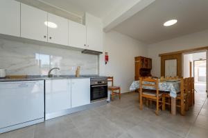 a kitchen with white cabinets and a dining room with a table at Casa Turalves - By WeHostMadeira in Porto Santo