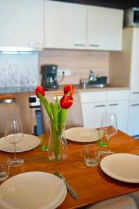 a wooden table with plates and red flowers in a vase at PrimeBnb Bad Hersfeld in Bad Hersfeld +12 photos