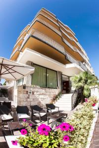 ein Gebäude mit Tischen, Stühlen und rosa Blumen in der Unterkunft Hotel Brig in Cattolica