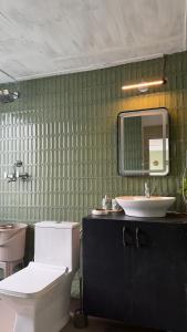 a bathroom with a sink and a toilet and a mirror at MATANAI HOUSE X THHP - The Deck Villa Mukteshwar - 2 Bedroom Bonfire & BBQ in Mukteshwar