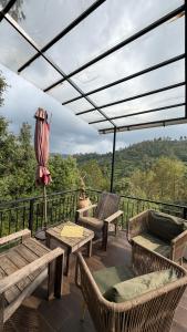 a patio with chairs and tables and a view of the forest at MATANAI HOUSE X THHP - The Deck Villa Mukteshwar - 2 Bedroom Bonfire & BBQ in Mukteshwar
